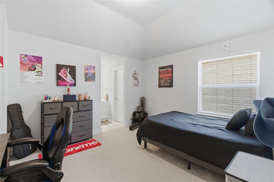 Upstairs carpeted bedroom featuring a single window with horizontal blinds, a neutral wall color, and a vaulted ceiling