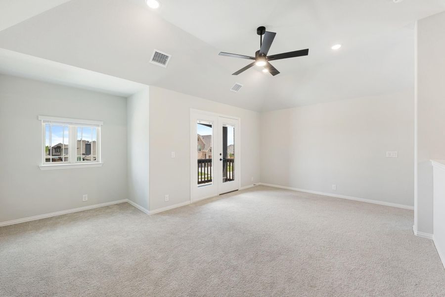Empty room with vaulted ceiling, ceiling fan, carpet flooring, and French doors leading to a balcony