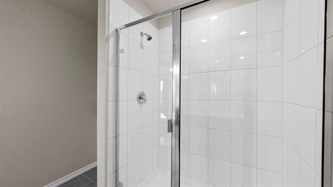 Shower with white tiled walls, a glass enclosure, and chrome fixtures