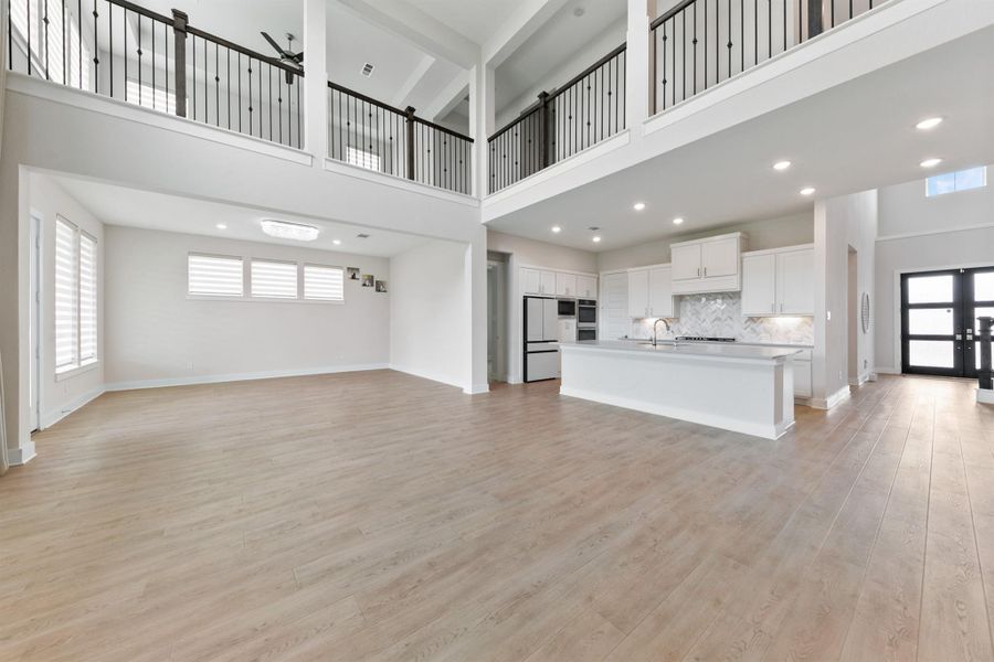 Expansive two-story living area with soaring ceilings, abundant natural light, and an open-concept design that creates a bright and airy atmosphere. The upstairs overlook adds architectural interest while enhancing the home’s spacious and connected feel.