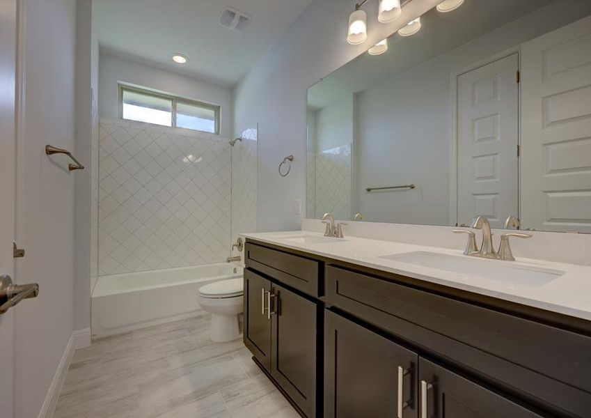 Guest bathroom with a double-sink vanity and a dual shower and tub that provides conveniences to all guests.