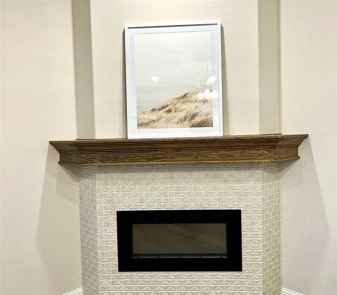 Corner fireplace with a wood-finish mantel and a white geometric tiled surround Corner fireplace with a wood-finish mantel and a white geometric tiled surround