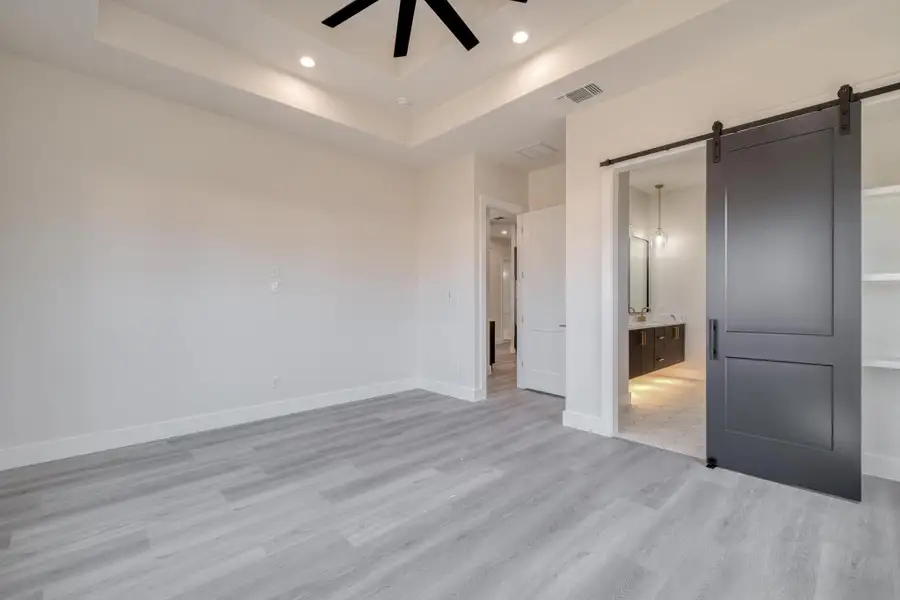 Unfurnished bedroom featuring baseboards, visible vents, light wood finished floors, recessed lighting, and a barn door