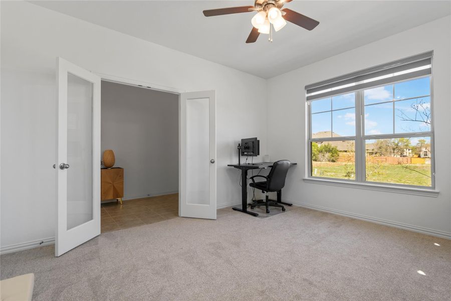 French doors open into this versatile home office with a ceiling fan and a view of the outside. French doors open into this versatile home office with a ceiling fan and a view of the outside.