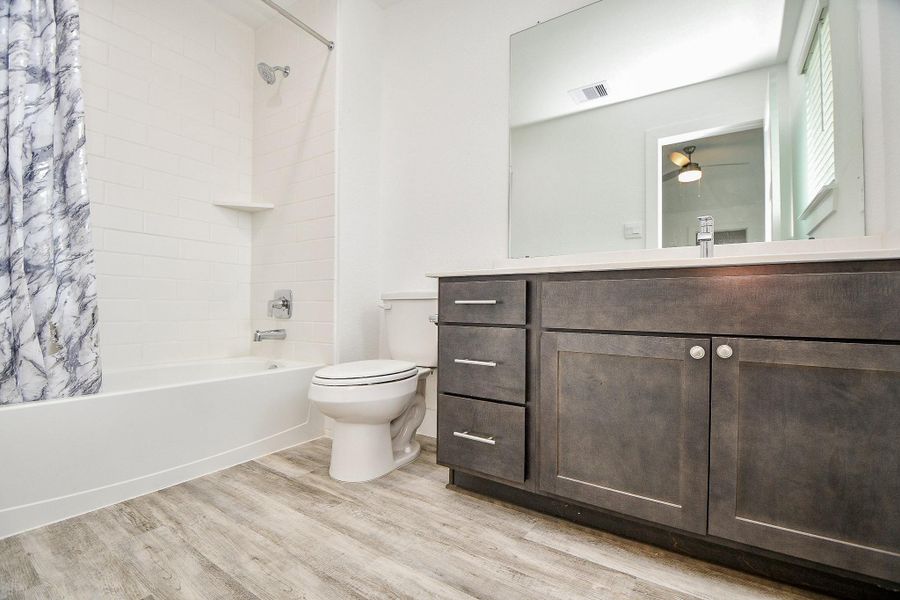 This second primary en suite bathroom showcases a modern design, including a large mirror, a dark wood vanity with ample storage, and a combined shower and bathtub. This second primary en suite bathroom showcases a modern design, including a large mirror, a dark wood vanity with ample storage, and a combined shower and bathtub.