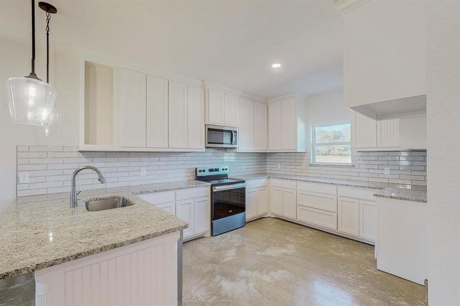 Kitchen featuring white cabinetry, pendant lighting, stainless steel appliances, and sink