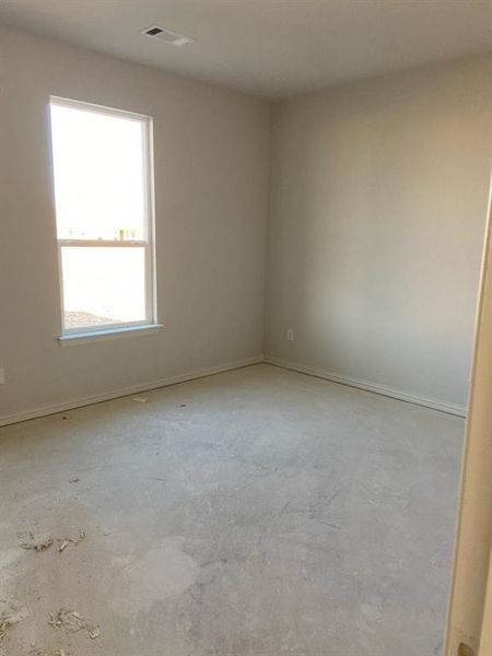 Spacious room featuring neutral painted walls, a large window, a ceiling vent, and a concrete subfloor