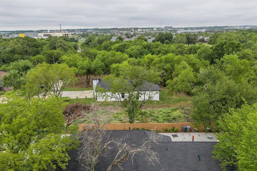 Aerial perspective showcasing a single-story residence with a white exterior, a dark roof, and a visible driveway Aerial perspective showcasing a single-story residence with a white exterior, a dark roof, and a visible driveway