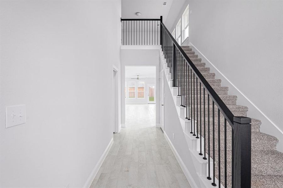 Stairs with plenty of natural light, a high ceiling, baseboards, and wood finished floors