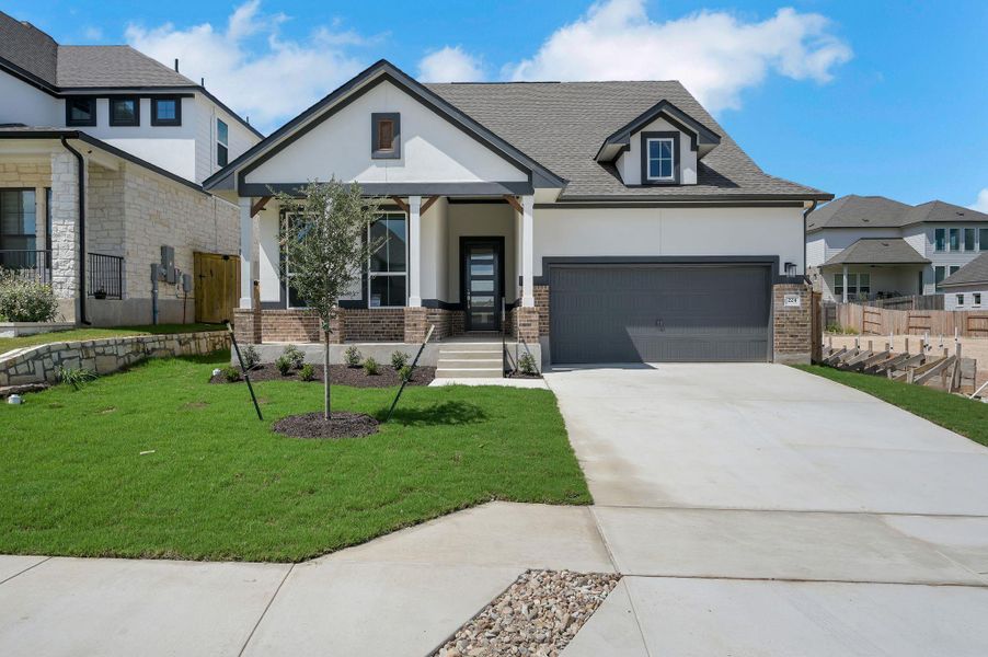 View of front of house with stucco siding, driveway, a shingled roof, and brick siding