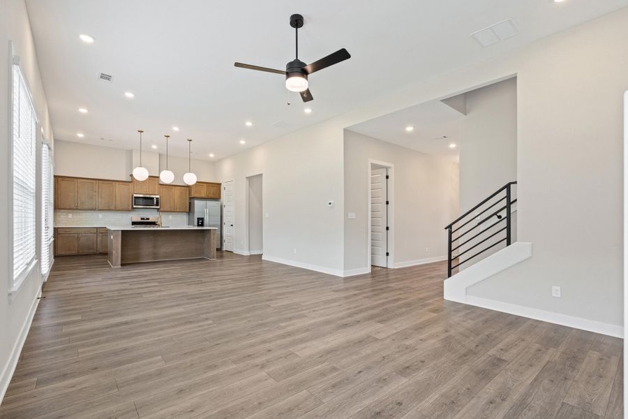 Open-concept living area featuring wood-finish flooring, recessed lighting, and a modern ceiling fan Open-concept living area featuring wood-finish flooring, recessed lighting, and a modern ceiling fan