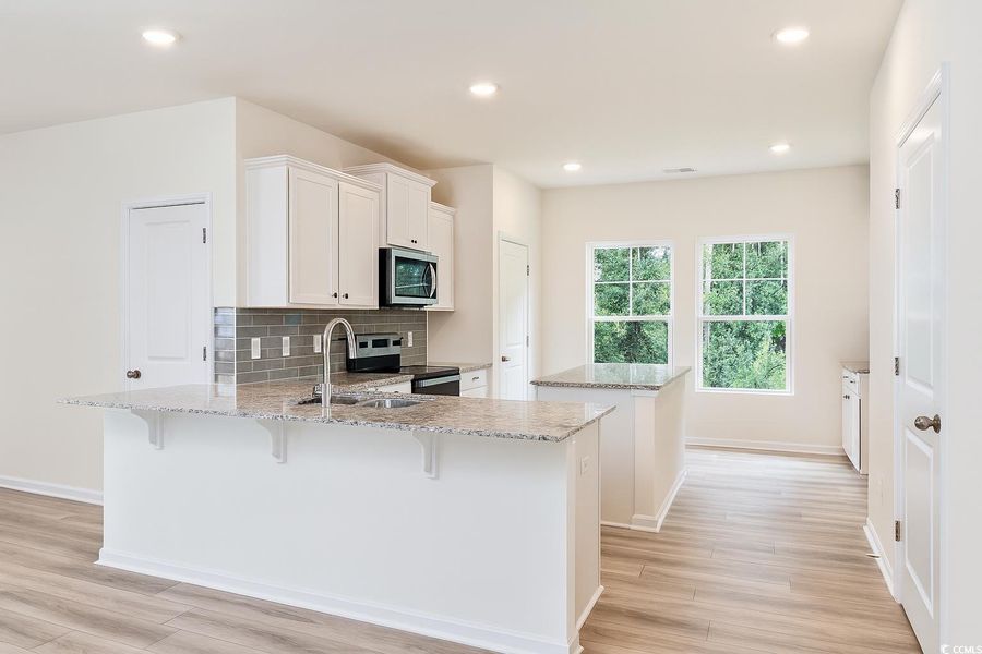 Kitchen with decorative backsplash, a center island, a peninsula, appliances with stainless steel finishes, and recessed lighting