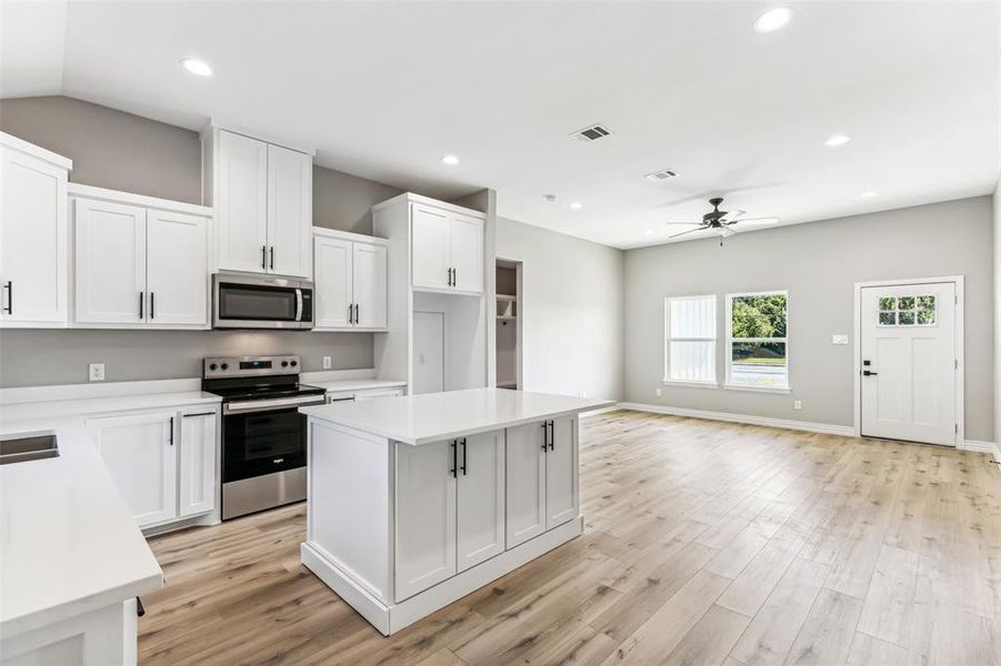 Kitchen featuring light hardwood / wood-style floors, a center island, stainless steel appliances, ceiling fan, and white cabinets