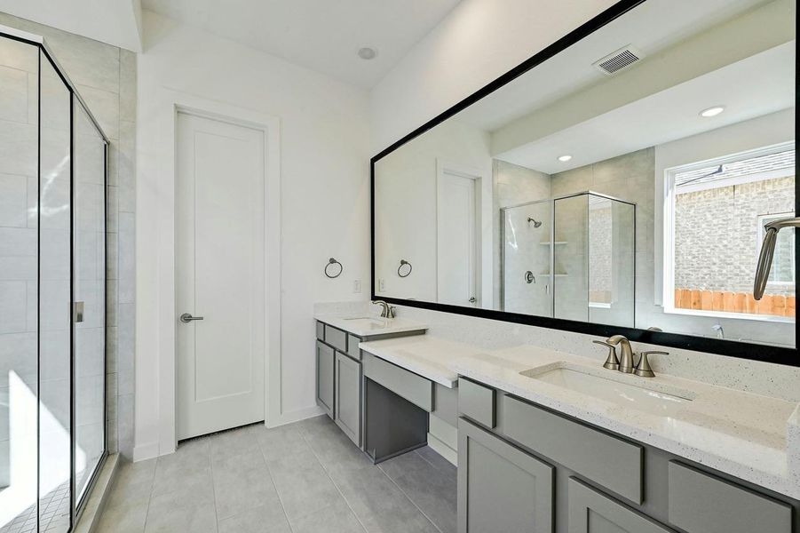 Bathroom featuring a stall shower, double vanity, and tile patterned flooring