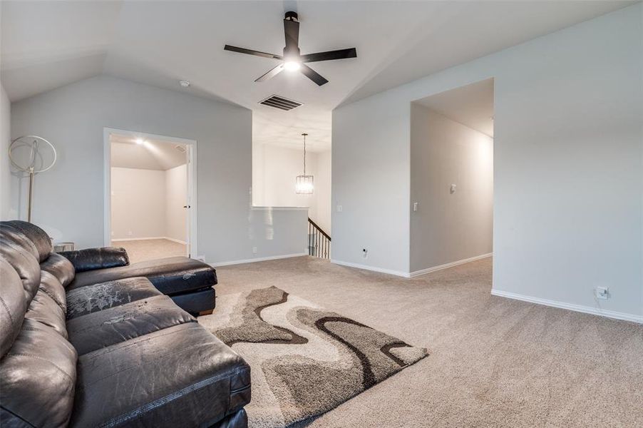 Carpeted living area with ceiling fan and vaulted ceiling Carpeted living area with ceiling fan and vaulted ceiling