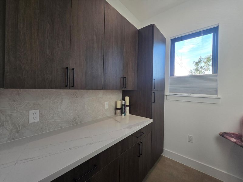 Rich wood cabinetry paired with marble-patterned countertops creates a refined storage area.