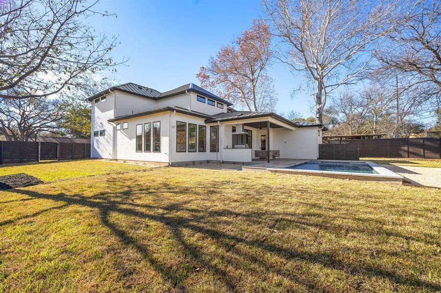 Rear view of property featuring a fenced backyard, a fenced in pool, stucco siding, and a yard