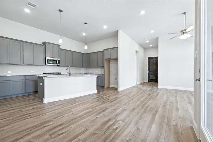 Kitchen featuring decorative backsplash, gray cabinetry, a ceiling fan, stainless steel microwave, and recessed lighting Kitchen featuring decorative backsplash, gray cabinetry, a ceiling fan, stainless steel microwave, and recessed lighting