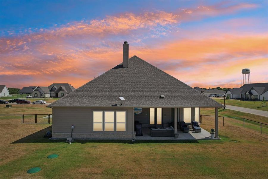 Back of property featuring covered patio and fenced backyard.