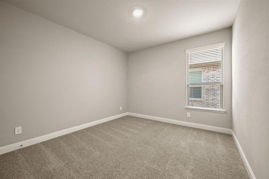 Another secondary bedroom with neutral carpet and window light, offering flexibility as a guest room, nursery, or playroom.