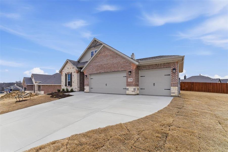 View of front of property with a garage, concrete driveway, stone siding, and brick siding