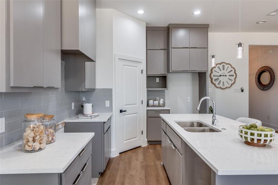 Kitchen with gray cabinetry, sink, light hardwood / wood-style floors, and backsplash