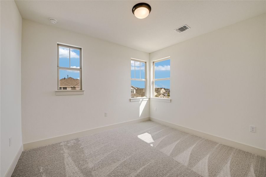 Carpeted spare room featuring healthy amount of natural light