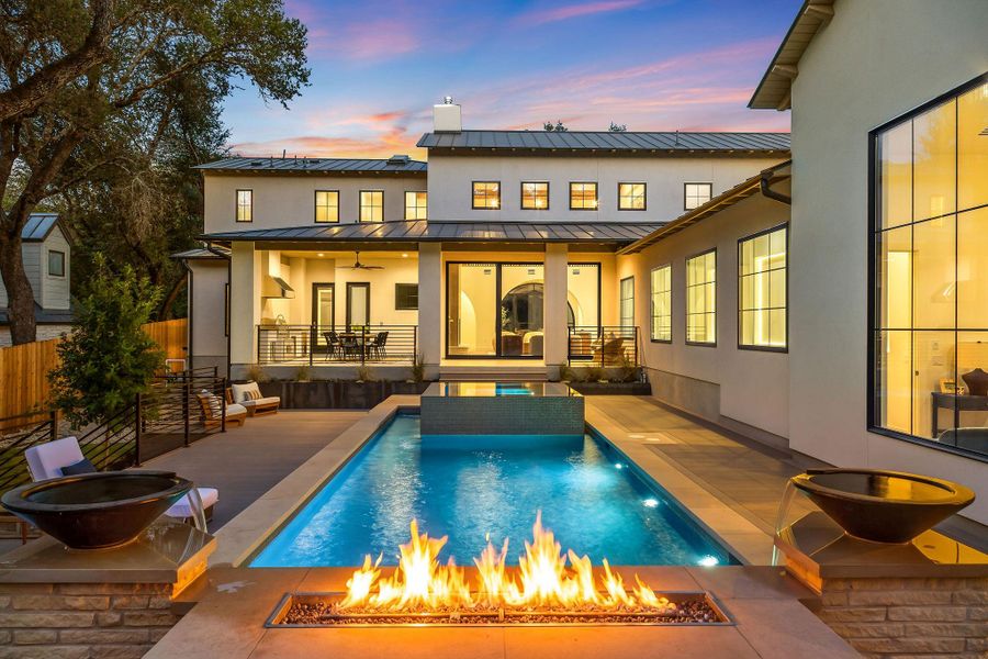 An inviting backyard oasis features a glistening pool with a raised spa, complemented by an outdoor living area and sun loungers.
