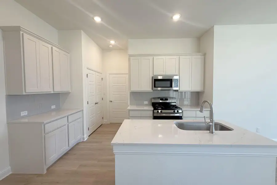 Kitchen featuring light-toned cabinetry, stainless steel appliances, an island with an undermount sink, and recessed lighting Kitchen featuring light-toned cabinetry, stainless steel appliances, an island with an undermount sink, and recessed lighting