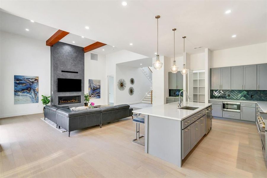 Kitchen featuring pendant lighting, a kitchen island with sink, open floor plan, gray cabinets, and a breakfast bar