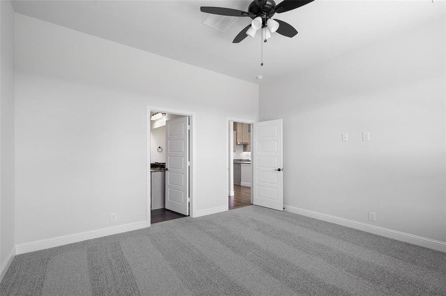 Unfurnished bedroom featuring dark colored carpet, connected bathroom, and a ceiling fan
