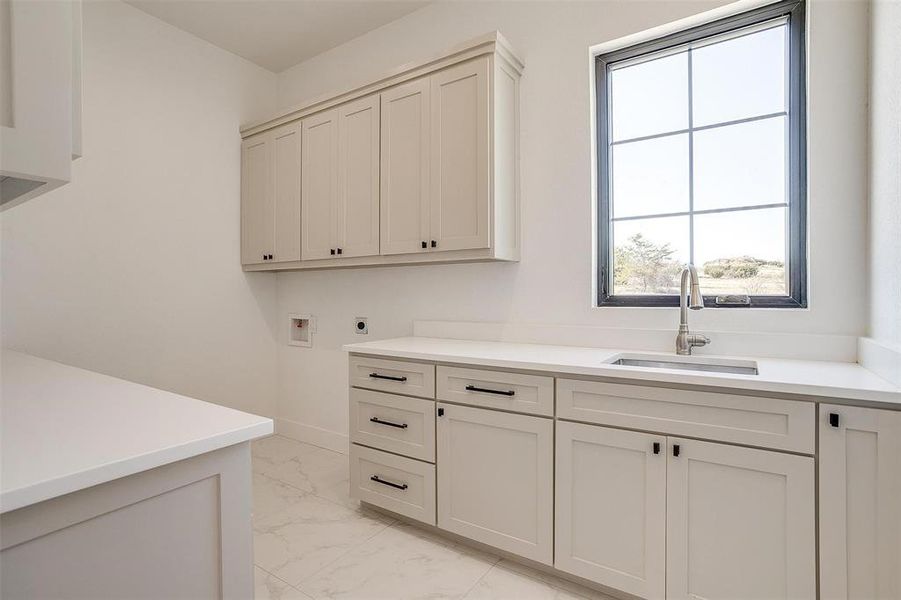 Laundry area featuring electric dryer hookup, cabinets, sink, and plenty of natural light