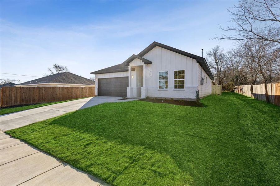 View of front facade featuring a front yard and a garage