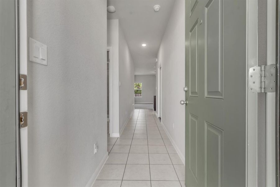 A welcoming entryway with cool-toned walls and durable tile flooring extends a clear path into the home.