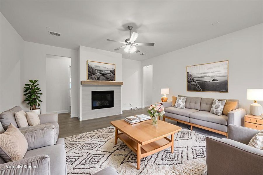 Living area featuring a ceiling fan, wood finished floors, a glass covered fireplace, and baseboards Living area featuring a ceiling fan, wood finished floors, a glass covered fireplace, and baseboards