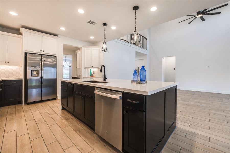 A true dream kitchen! Gleaming quartz , high-end stainless steel appliances, stylish modern lighting, an island with storage, spacious walk-in pantry beautiful countertops & backsplash, paired with chic dark cabinets