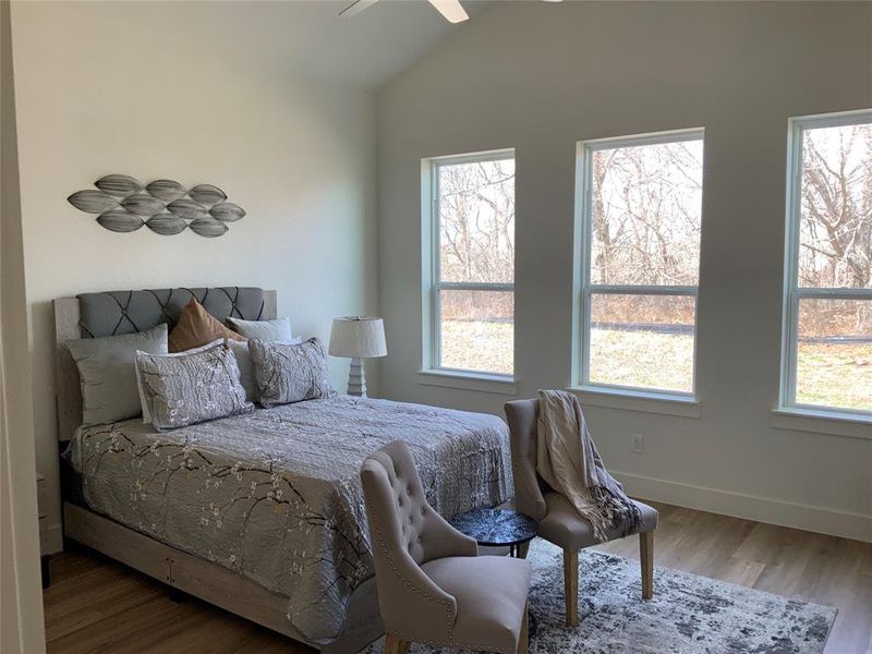 Bedroom featuring wood finished floors, vaulted ceiling, and a ceiling fan Bedroom featuring wood finished floors, vaulted ceiling, and a ceiling fan