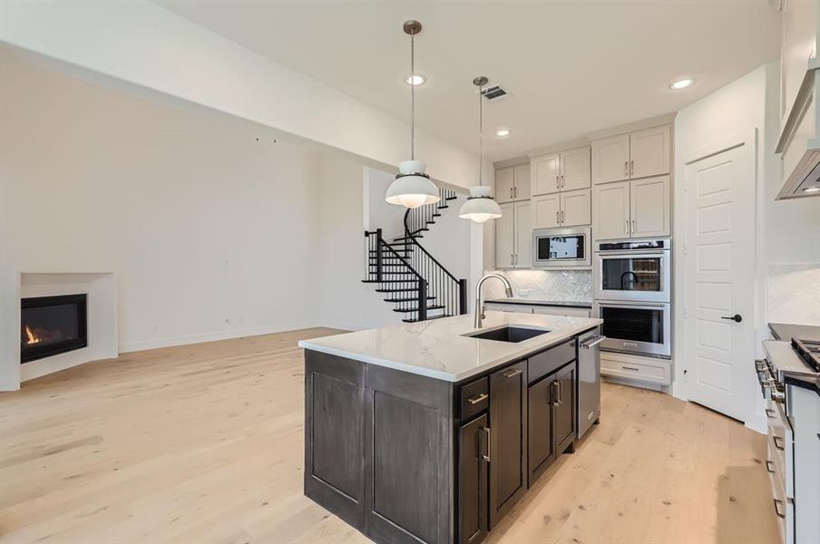 Kitchen with sink, tasteful backsplash, stainless steel appliances, and light hardwood / wood-style floors