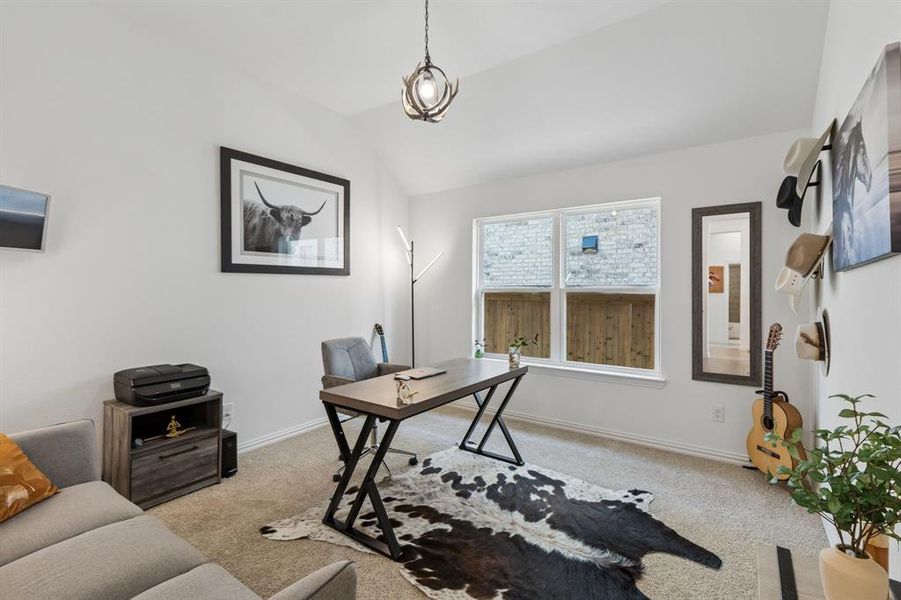 Vaulted ceiling room featuring a large window, neutral carpet flooring, and a modern antler-style chandelier