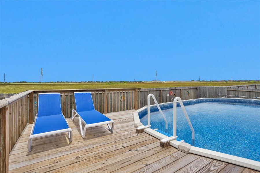 Expansive wooden deck allows for tanning and entry into the above-ground pool.