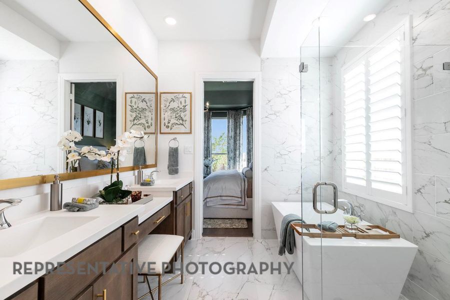 Ensuite bathroom featuring marble tiled floors, vanity, a soaking tub, tile walls, and a marble finish shower Ensuite bathroom featuring marble tiled floors, vanity, a soaking tub, tile walls, and a marble finish shower