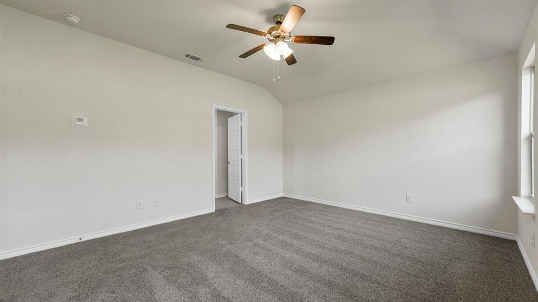 Spacious room featuring neutral carpeting, light-colored walls, a ceiling fan with integrated lighting, and a window providing natural illumination