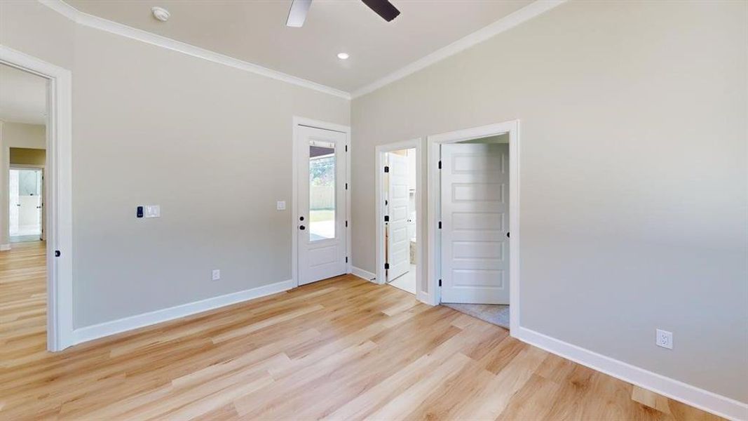 Unfurnished room featuring light wood-type flooring, ceiling fan, a smoke detector, crown molding, and baseboards