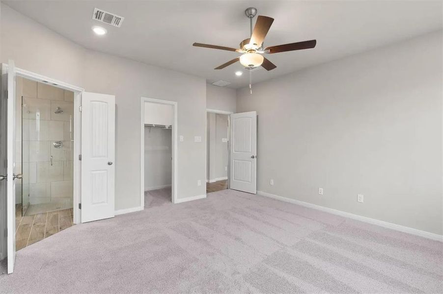 A comfortable bedroom with soft carpet flooring provides direct access to a well-appointed bathroom and a spacious walk-in closet.