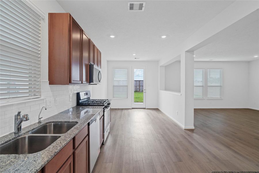 An open-concept kitchen provides a clear view into the adjacent dining nook, creating a cohesive space for cooking and gathering. The kitchen is also equipped with an undermount double-bowl sink and a Moen kitchen faucet.