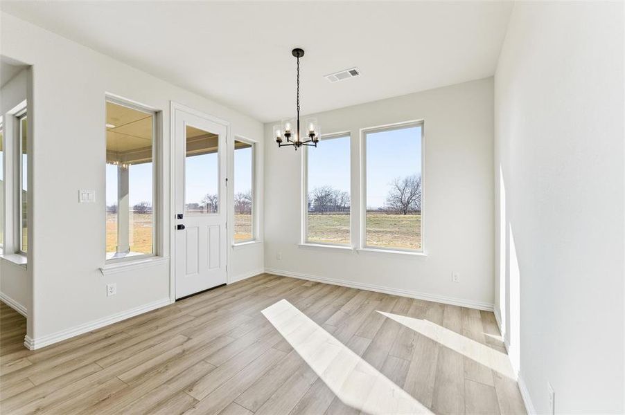 Unfurnished dining area featuring light wood finished floors and a chandelier