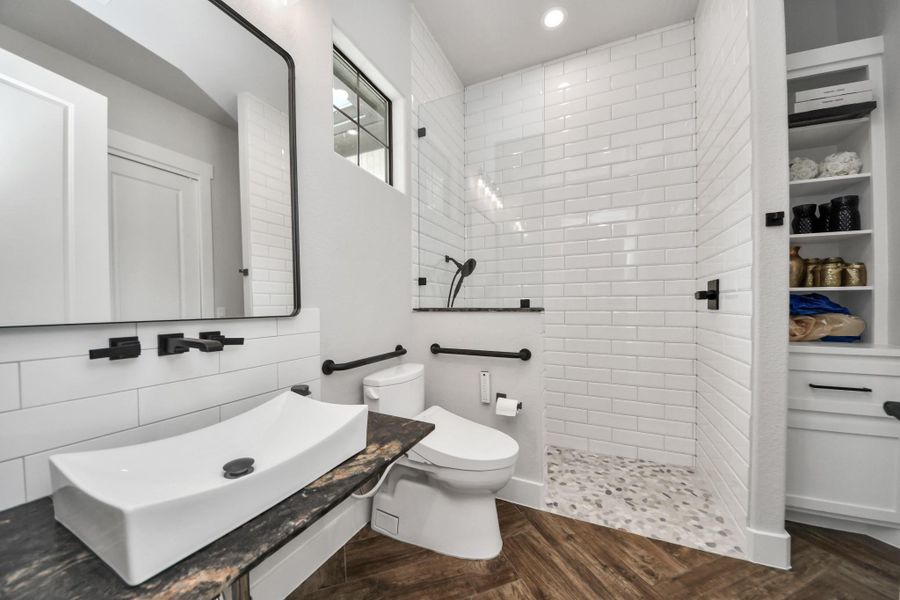 Stylish bathroom featuring a modern vessel sink, sleek black fixtures, a spacious walk-in shower with elegant subway tiles, and a convenient built-in shelving unit.