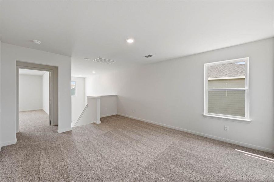 Empty room with light colored carpet and recessed lighting
