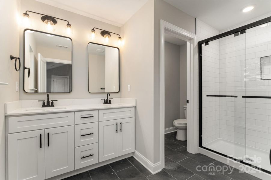 Primary en-suite bathroom with floor to ceiling tile shower and tile floors (Representative Photo)