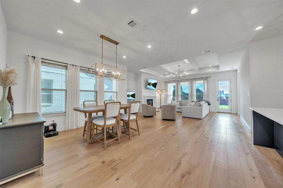 Dining space with a chandelier, a raised ceiling, and light hardwood / wood-style flooring